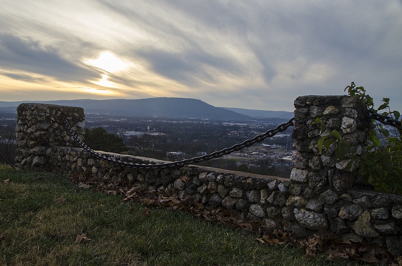 Chattanooga and Lookout Mountain in the distance, against a setting sun, are pictured from a stone wall on Missionary Ridge.