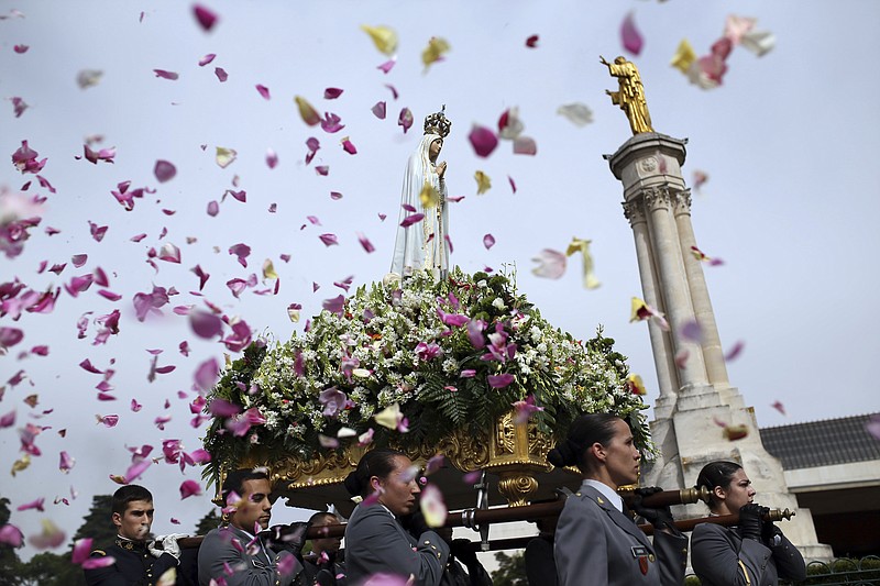 Worshippers throw flower petals at the statue of the Our Lady of Fatima as it is carried at the Our Lady of Fatima shrine in central Portugal. The centennial of the miracle will be observed in 2017 with a visit by the pope.