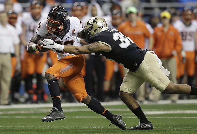 
              Oklahoma State running back Chris Carson, left, is hit by Colorado linebacker Rick Gamboa as he runs for a first down during the second half of the Alamo Bowl NCAA college football game, Thursday, Dec. 29, 2016, in San Antonio. (AP Photo/Eric Gay)
            