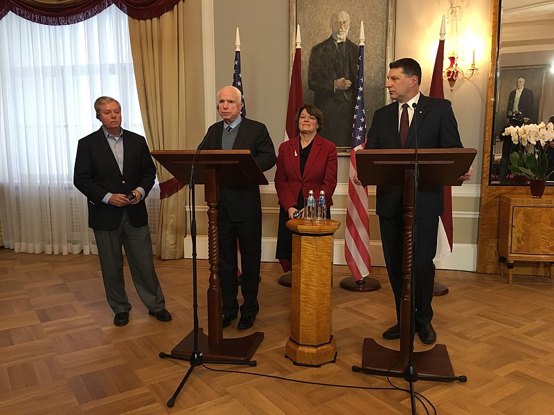 Latvian President Raimonds Vejonis, right, looks at US Sen. John McCain centre left, during a press conference, Wednesday, Dec. 28, 2016 in Riga, Latvia, while Lindsey Graham, R-SC., and Amy Klobuchar, D-Minn., stand in the background. Russia can expect hard-hitting sanctions from United States lawmakers if an investigation proves that Moscow interfered in the presidential election, a U.S. senator said Wednesday during a visit to Latvia. 