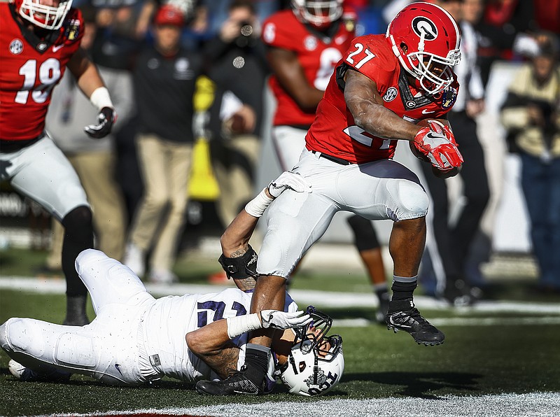 Georgia running back Nick Chubb (27) runs over TCU defender Niko Small for a touchdown in the fourth quarter of the Liberty Bowl NCAA college football game, Friday, Dec. 30, 2016, in Memphis, Tenn. (Mark Weber/The Commercial Appeal via AP)