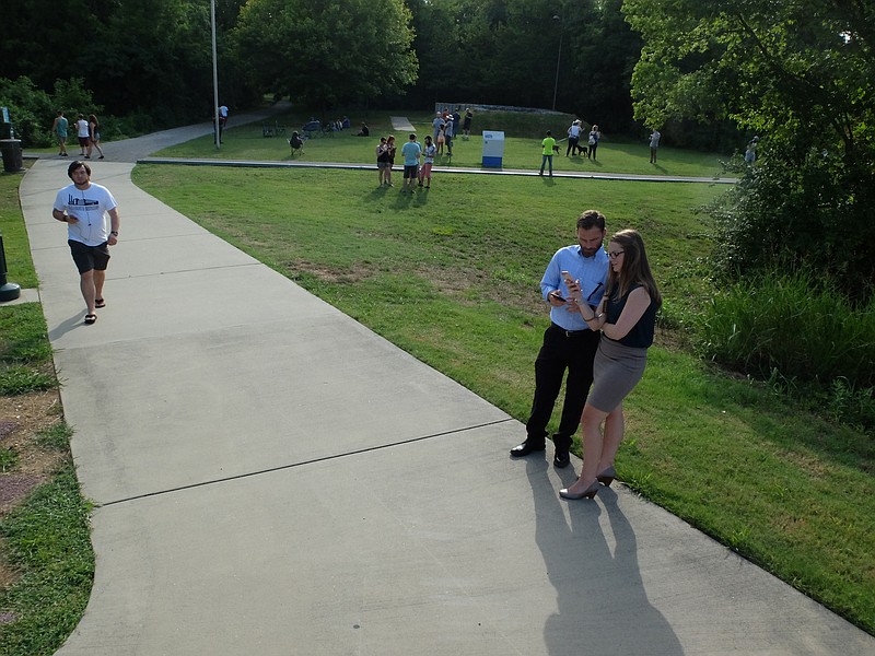 Staff photo by Tim Barber Brooke Bennett and Trevor Jackson look at their phones as they play the PokemonGo app at Renaissance Park on Tuesday evening. "We're on a Pokemon date," Jackson said. "Instead of dinner and a movie, it's dinner and Pokemon for us."