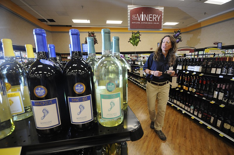 Mara McVicker, growler station lead for Food City, hangs tags on various bottles of wine at the St. Elmo store.