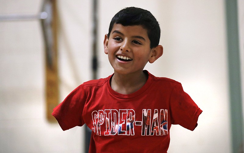 
              In this Dec. 10, 2016 photo, Syrian refugee Ahmad Alkhalaf smiles while playing with friends during a day camp for local Muslim children in Sharon, Mass. "Anything is possible in this world. You just have to believe in yourself," says Ahmad, whose arms were blown off above the elbows in a refugee camp bomb blast in 2014, which also killed three of his brothers. (AP Photo/Charles Krupa)
            