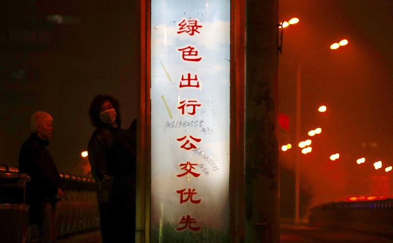 
              A pedestrian wearing a mask looks back while passing by a slogan that reads: "If you want to go out, please take a public bus" in Beijing Monday, Jan. 2, 2017. Beijing and other cities across northern and central China were shrouded in thick smog Monday, Jan. 2, 2017, prompting authorities to delay dozens of flights and close highways. (AP Photo/Andy Wong)
            