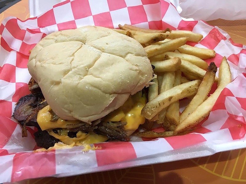 Served with a side of fries, the pork belly burger at Fat Boy's Roadside Eats tops an ample beef patty with a slab of pork belly, cheese sauce and grilled onions.