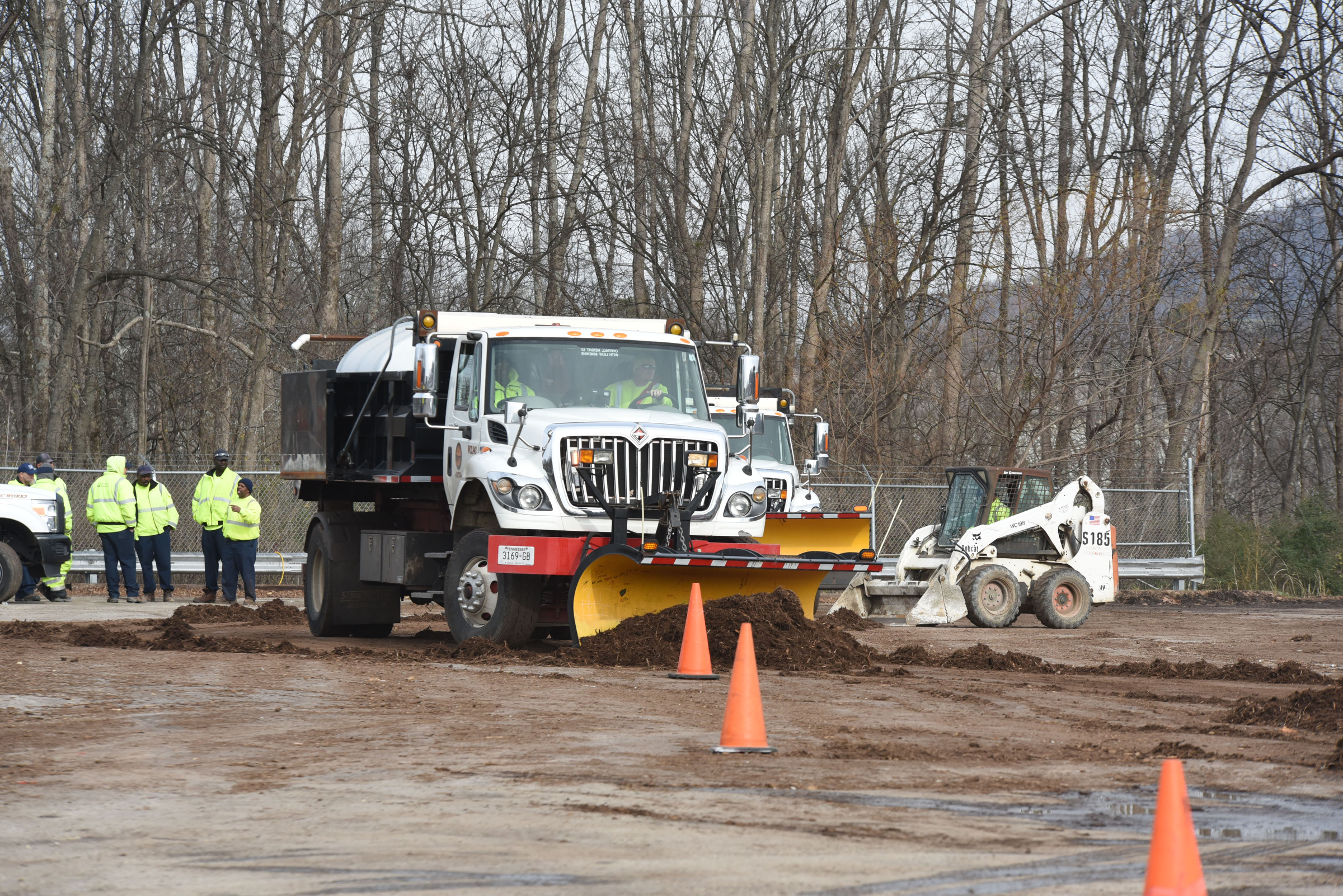 Street maintenance crews train between cones with snow plows on multi-use trucks at the city's wood recycle yard on North Hawthorne Street. The cones are used to simulate parked cars requiring precise maneuverability.