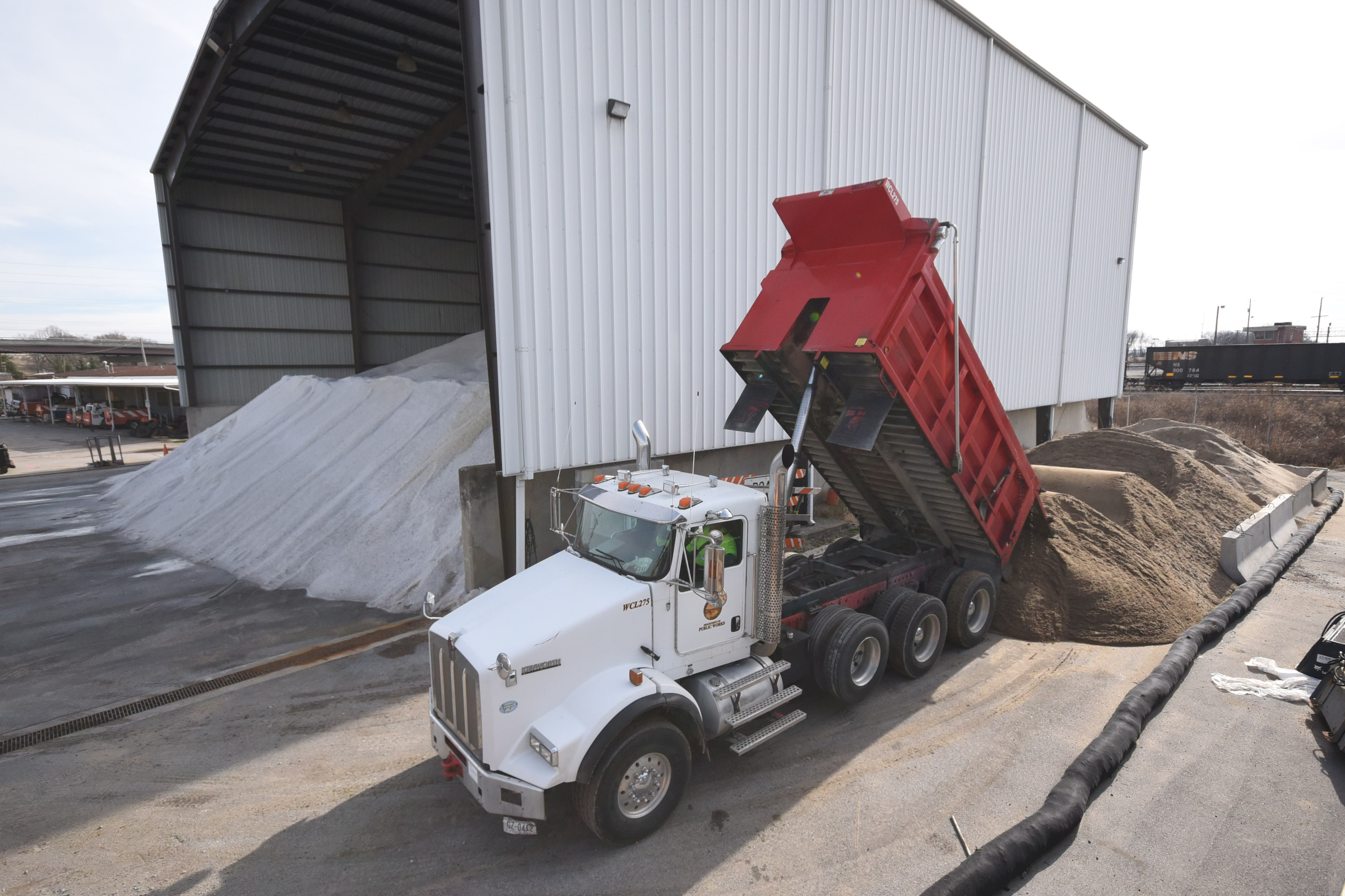 City truck driver Patrick Davis dumps his second load of sand beside the salt barn at the city yard just off E. 11th Street on Wednesday. "It is my second load of 25-tons today," Davis said.