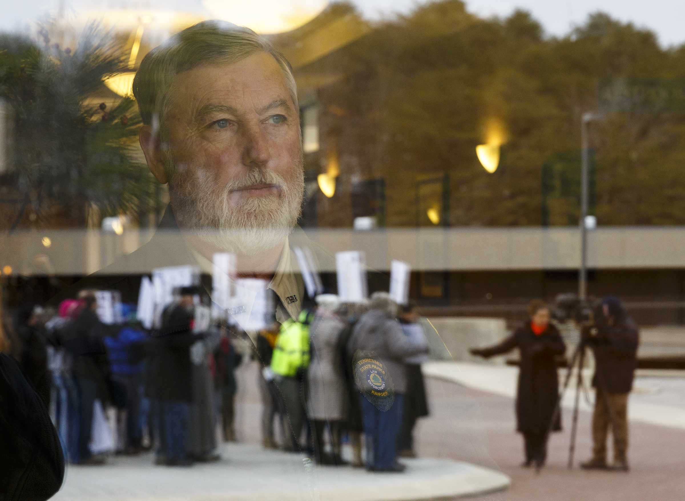 Park ranger Robin Bayless watches demonstrators protesting the privatization of the Fall Creek Falls State Park's hospitality services outside of the park's inn on Thursday, Jan. 5, 2017, near Spencer, Tenn. The Tennessee State Employees Association organized the protest, which coincided with a meeting by state officials and potential bidders at the park's inn.