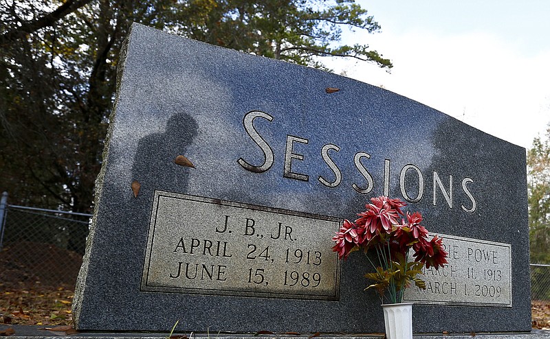 
              In this photo taken Dec. 6, 2016, Les Johnson, 69, of Camden, Ala., a family friend of Attorney General-designate, Sen. Jeff Sessions, R-Ala. is seen in the reflection of Sessions's parents tombstone at the Bell's Landing Presbyterian Church cemetery in Bell's Landing, Ala. (AP Photo/Brynn Anderson)
            