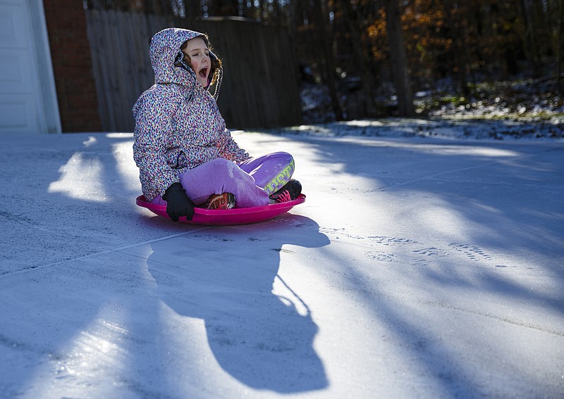 Isa Baez slides down her family's icy driveway after an overnight winter storm brought snow to the region Saturday, Jan. 7, 2017, in Chattanooga, Tenn. Icy roads caused headaches for motorists as the temperatures dropped into the teens overnight.