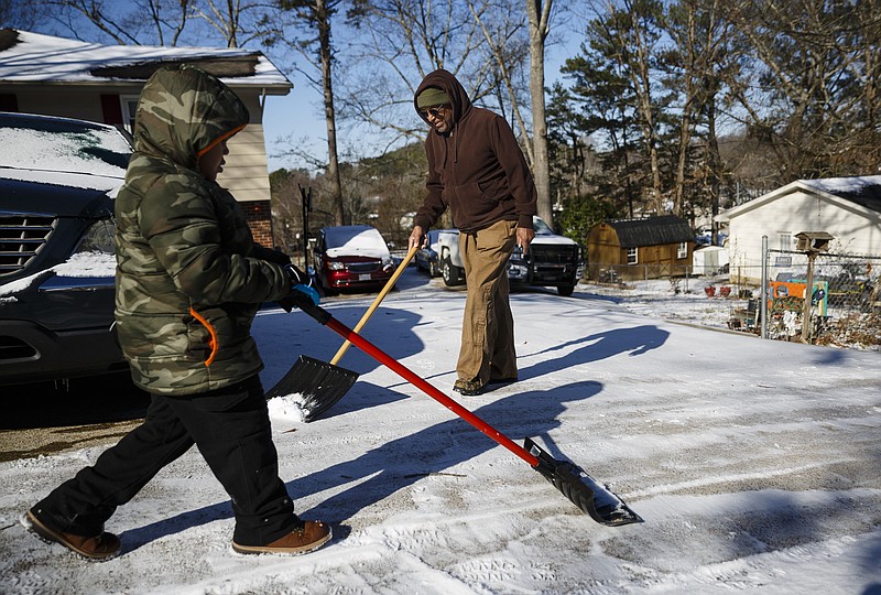Jaden Trammell, left, helps his grandfather Melvin Brummitt shovel snow from their driveway after an overnight winter storm brought snow to the region Saturday, Jan. 7, 2017, in Chattanooga, Tenn. Icy roads caused headaches for motorists as the temperatures dropped into the teens overnight.