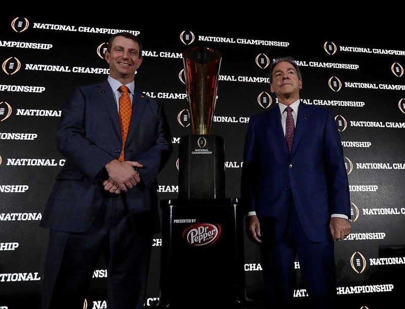 Clemson football coach Dabo Swinney and Alabama counterpart Nick Saban pose Sunday beside the trophy that will be awarded after tonight's national championship game in Tampa, Fla.