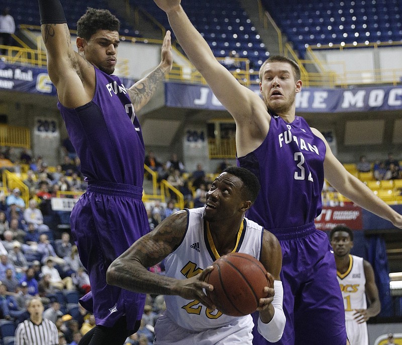 UTC forward Tre' McLean tries to find room for a shot between Furman's Matt Rafferty, right, and Kris Acox, left, during the Mocs' home basketball game against Furman at McKenzie Arena on Saturday, Jan. 7, 2017, in Chattanooga, Tenn.