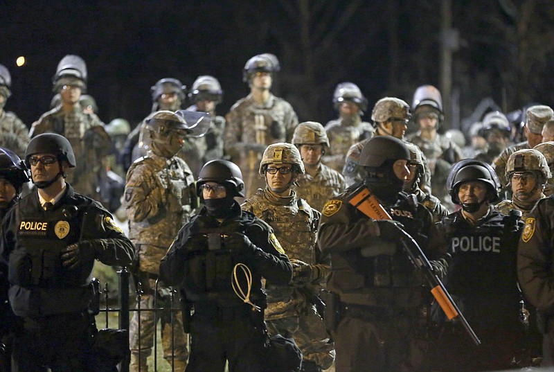 
              FILE - In this Friday, Nov. 28, 2014, file photo, police and Missouri National Guardsmen stand guard as protesters gather in front of the Ferguson Police Department, in Ferguson, Mo. The so-called "Ferguson effect" — officers backing off of policing out of fear that their actions will be questioned after the fact — has been talked about but never really quantified. A new study suggests the effect is a reality, with three-quarters of officers surveyed saying they are hesitant to use force, even when appropriate, and are less willing to stop and question suspicious people. (AP Photo/Jeff Roberson, File)
            
