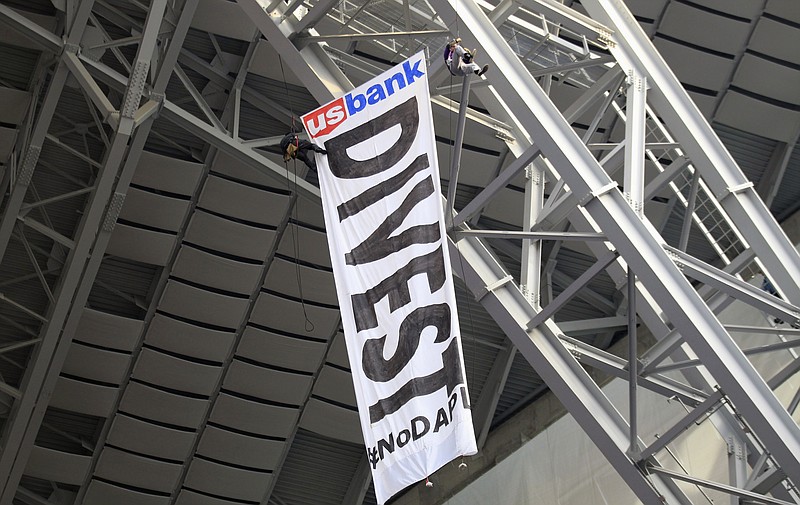 
              FILE - In this Jan. 1, 2017, file photo, protesters against the Dakota Access Pipeline rappel from the catwalk after placing a banner in U.S. Bank Stadium during an NFL football game between the Minnesota Vikings and Chicago Bears in Minneapolis. The front lines of the battle against the $3.8 billion Dakota Access pipeline are shifting away from the dwindling encampment in North Dakota. (AP Photo/Andy Clayton-King, File)
            