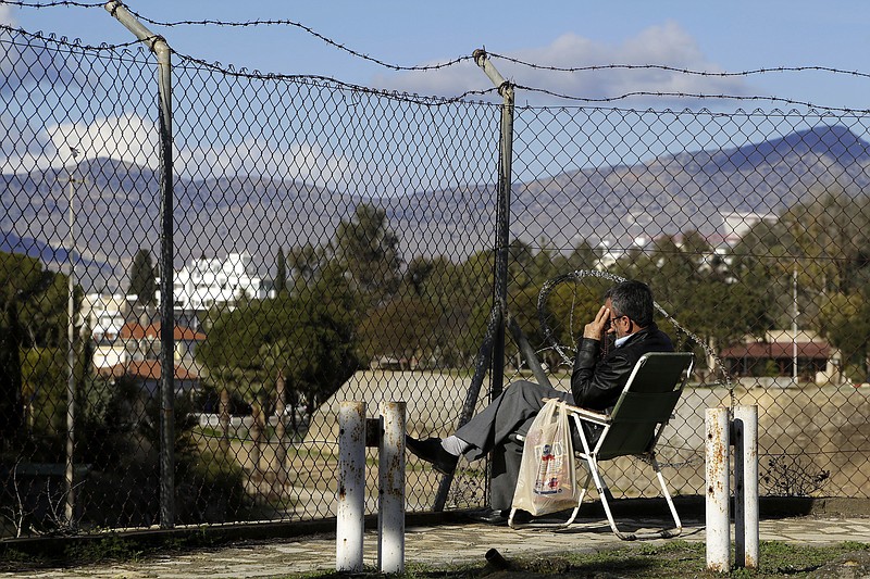 
              A man sits in front of the fence that divides the Greek and Turkish Cypriots areas, as he watches from the Turkish Cypriots breakaway northern part of the divided capital Nicosia in the eastern Mediterranean island of Cyprus, Wednesday, Jan. 11, 2017. The rivals leaders of Cyprus have begun a third day of talks aimed at reunifying the island split along ethnic Greek and Turkish lines. The talks will take on an international dimension on Thursday with the arrival of leaders from Britain, Greece and Turkey. (AP Photo/Petros Karadjias)
            