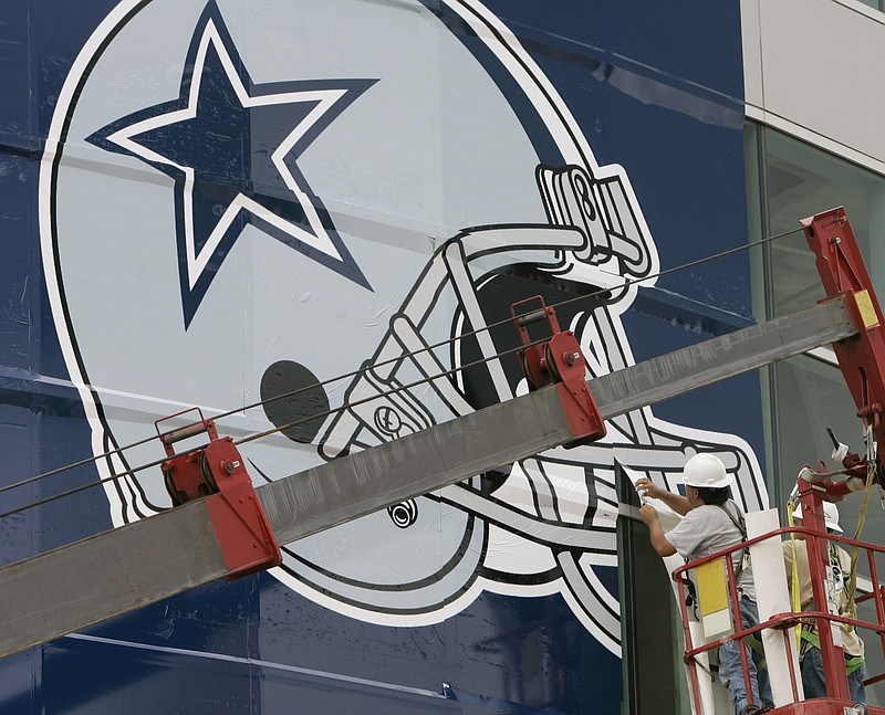 
              FILE - In this July 24, 2007, file photo, workers hang a Dallas Cowboys logo on the Alamodome in preparation for football training camp in San Antonio. WFAA-TV reported on Jan. 10, 2017 that a Texas baby hospitalized with a congenital heart defect calms down when watching Cowboys games. (AP Photo/Eric Gay, File)
            