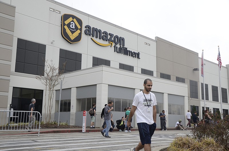 An Amazon employee walks in front of the Amazon sign while workers take a break on Cyber Monday at the Amazon Fulfillment Center in the Enterprise South Industrial Park in Chattanooga, Tenn., on Monday, December 1, 2014.