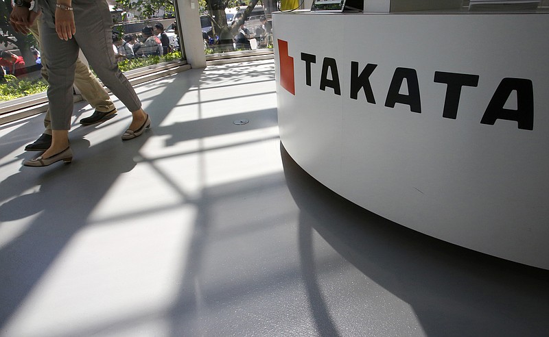 In this May 4, 2016, file photo, visitors walk by a Takata Corp. desk at an automaker's showroom in Tokyo. The Justice Department is planning to announce a criminal penalty against the Japanese air bag maker as part of its investigation into the company's defective air bag inflators. The department has scheduled a news conference Friday, Jan. 13, 2017 in Detroit to make the announcement. (AP Photo/Shizuo Kambayashi, File)