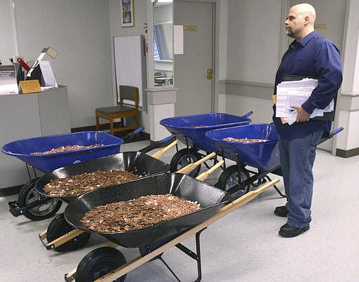 Nick Stafford waits for his number to be called Wednesday, Jan. 11, 2017, as he stands beside of 5 wheelbarrows full of change, mostly pennies, at the DMV in Lebanon, Va. Stafford was paying the sales tax on two cars that he was titling. Stafford had paid $165 to file three lawsuits in Russell County General District Court: two against specific employees at the Lebanon DMV and one against the DMV itself., which means he spent $1,005 to get 10 phone numbers and the satisfaction of delivering 300,000 pennies. Not to mention the nearly $3,000 he paid the DMV for the cars. (David Criggeru/The Bristol Herald-Courier via AP)