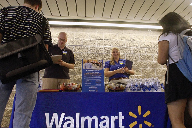 In this Sept. 1, 2011, photo, Wal-Mart employees Jon Christians and Lori Harris take job applications and answers questions during a job fair at the University of Illinois Springfield campus in Springfield, Ill. Trying to stem high turnover in store jobs, a nonprofit group and chains such as Wal-Mart and the Home Shopping Network are launching a program to help people develop the skills to land entry-level jobs and advance in a retail career.(AP Photo/Seth Perlman)