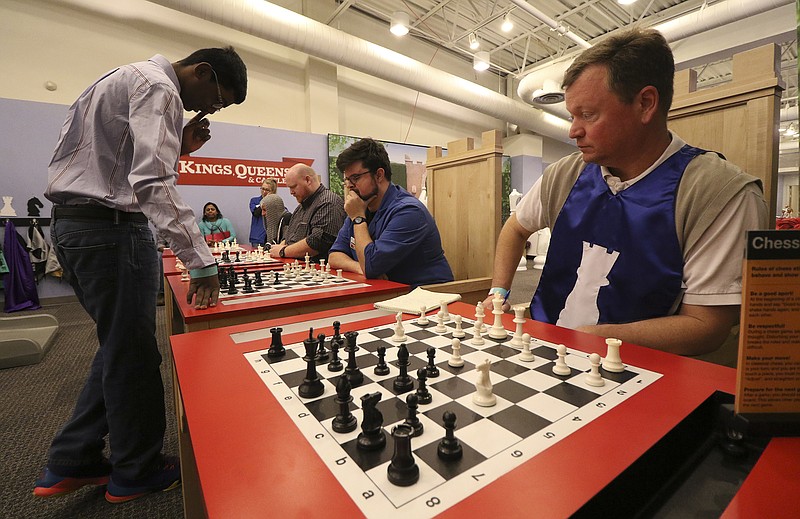 Suhas Gummadi, a 14-year-old East Hamilton High School freshman, plays chess against four opponents, including Times Free Press columnist Jay Greeson, right, at the Creative Discovery Museum on Monday. Gummadi won all four matches.