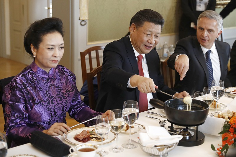 
              China's President Xi Jinping, center, Xi's wife Peng Liyuan, left, and Swiss Foreign Minister Didier Burkhalter eat Swiss cheese fondue during lunch during Xi's two days state visit to Switzerland in Bern, Switzerland, Monday, Jan. 16, 2017.  (Peter Klaunzer/Pool Photo via AP)
            