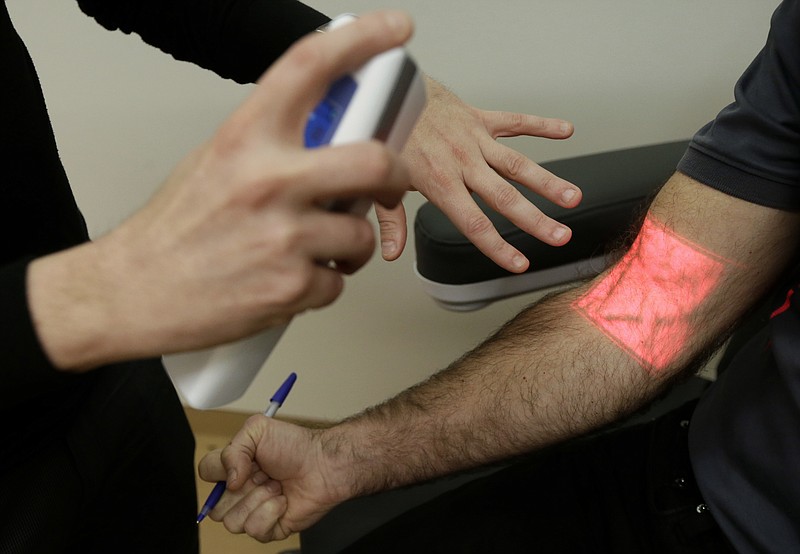 
              In this Jan. 10, 2017 photo, Adrian Aoun, founder and CEO of Forward, left, gives a demonstration of a vein illumination device that uses infrared light on an Associated Press reporter at a medical office in San Francisco. After a relative suffered a heart attack a few years ago, Silicon Valley entrepreneur Aoun got an up-close look at a health-care system that he diagnosed as an inefficient and outdated mess. Now, Aoun is ready to prescribe his remedy. It's called Forward, a health-management service that charges a $149 per month, roughly $1,800 a year, to tend to all of its patients' primary-care needs. (AP Photo/Jeff Chiu)
            