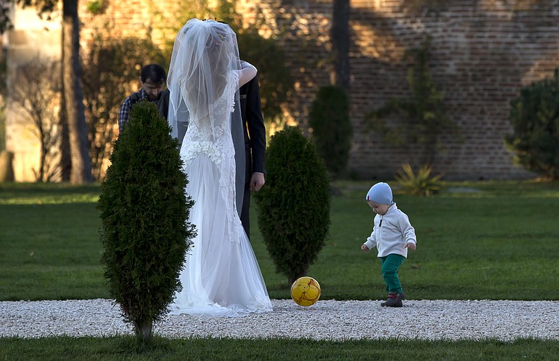 
              FILE - In this Nov. 9, 2013 file photo, a child plays with a ball next to a couple posing for a photographer in a park outside Bucharest, Romania. Newlywed couples took advantage of the unusual warm weather for the month of November, with temperatures reaching 20 degrees Celsius (68 degrees Fahrenheit), for outdoor photo sessions. Kiss goodbye some of those postcard-perfect, ideal-for-outdoor-wedding days. A new study said global warming is going to steal some of those exceedingly pleasant weather days from our future. On average, Earth will have four fewer days of mild and mostly dry weather by 2035 and ten fewer of them by the end of the century, according to a first-of-its-kind projection of nice weather. 
(AP Photo/Vadim Ghirda, File)
            