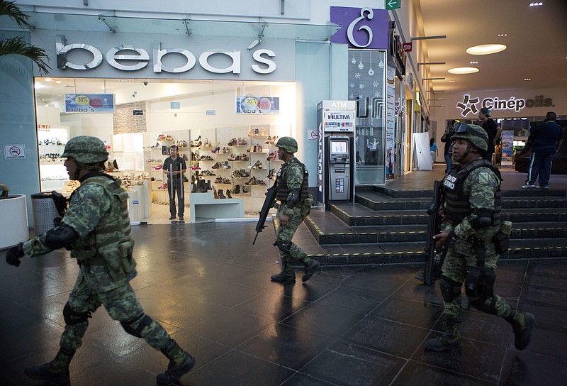 
              Soldiers walk inside Plaza Las Americas mall following reports of gunfire in Cancun, Mexico, Tuesday, Jan. 17, 2017. Gunmen attacked the state prosecutor's office in this Caribbean resort city Tuesday, ratcheting up tensions just a day after a deadly shooting at a music festival in a nearby town. (AP Photo/Rebecca Blackwell)
            