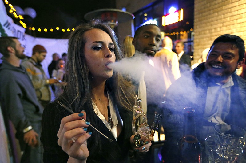
              FILE - In this Dec. 31, 2013, file photo, partygoers smoke marijuana during a Prohibition-era themed New Year's Eve party at a bar in Denver, celebrating the start of retail pot sales. Denver is starting work on becoming the first city in the nation to allow marijuana clubs and public pot use in places like restaurants, yoga studios and art galleries. Voters narrowly approved the "social use" measure last November. (AP Photo/Brennan Linsley, File)
            