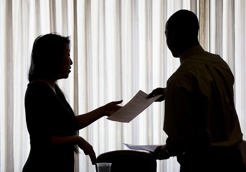 FILE - In this June 23, 2014, file photo, a recruiter, at left, takes the resume of an applicant during a job fair, in Philadelphia. On Thursday, Jan. 12, 2017, the Labor Department reports on the number of people who applied for unemployment benefits the week before. (AP Photo/Matt Rourke, File)