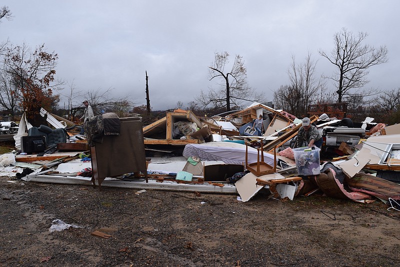 The home of Julie Crow and her brother, Shane Allison, was reduced to rubble by a tornado that ripped through Northeast Alabama late Tuesday or early Wednesday, At right, a family member picking though the pieces of the home is just in front of a car buried under the rubble of the home.
