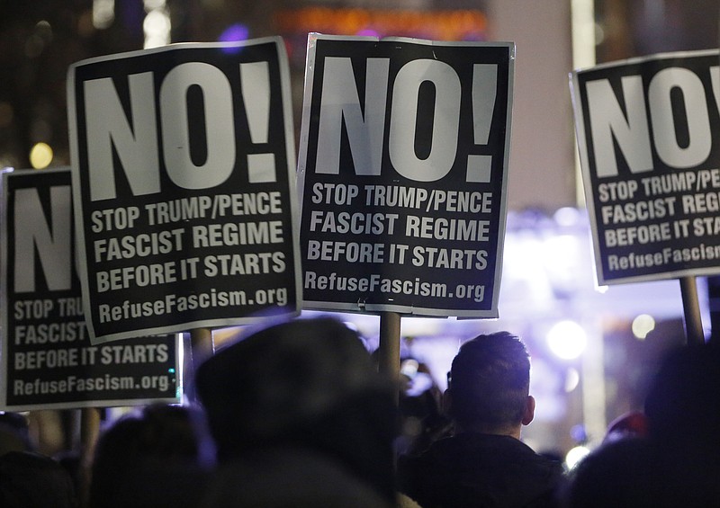 
              People attending an anti-Trump rally and protest hosted by filmmaker Michael Moore hold signs as they listen to speakers on a stage set up in front of the Trump International Hotel, Thursday, Jan. 19, 2017, in New York. President-elect Donald Trump, a New Yorker, is scheduled to take the oath of office Friday in Washington. (AP Photo/Kathy Willens)
            