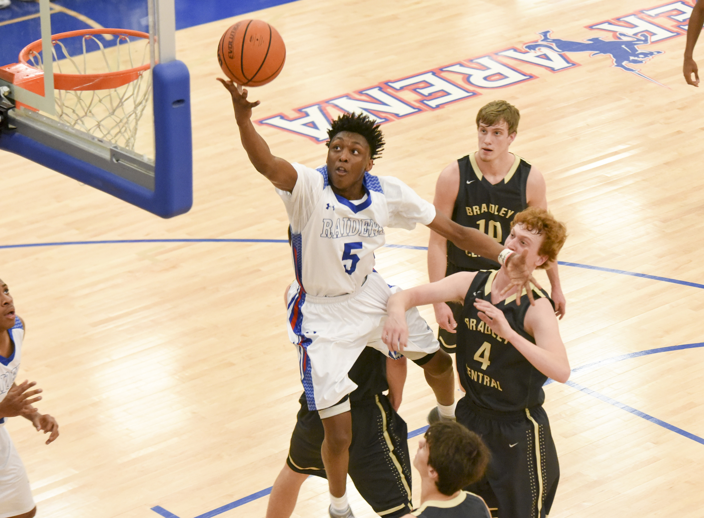 Cleveland's K.K. Curry (5) leaves Bradley Central's Trevor Cartwright (4) and Cole Copeland in the paint as he leaps among three defenders for a layup during the first half of Friday night's game hosted by Cleveland, which won 71-44.