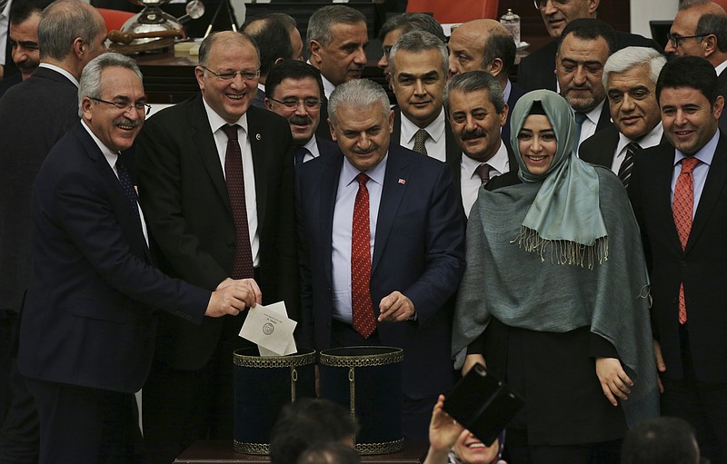 
              Turkey's Prime Minister, Binali Yildirim, centre, accompanied by some of his lawmakers cast their votes during Turkey's parliament debate proposing amendments to the country's constitution that would hand President Recep Tayyip Erdogan's largely ceremonial presidency sweeping executive powers, in Ankara, Turkey, early Saturday, Jan. 21, 2017. (AP Photo/Burhan Ozbilici)
            