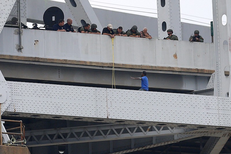 
              Sylvester Holt, bottom right, pleads with officers as while standing on the ledge of the Crescent City Connection Friday, Jan. 20, 2017, in New Orleans. Holt was wanted in the connection with the shooting of his wife and a Westwego police officer. (AP Photo/Jonathan Bachman)
            