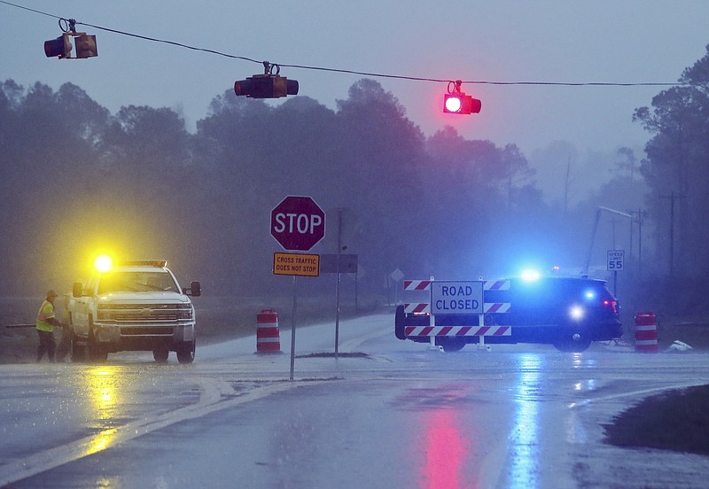 
              A Brooks County Sheriff and officials block Highway 122 as power line workers repair a downed pole in the background Sunday, Jan. 22, 2017, near Barney, Ga. The National Weather Service said Sunday that southern Georgia, northern Florida and the corner of southeastern Alabama could face "intense and long track" tornadoes, scattered damaging winds and large hail. (AP Photo/Phil Sears)
            
