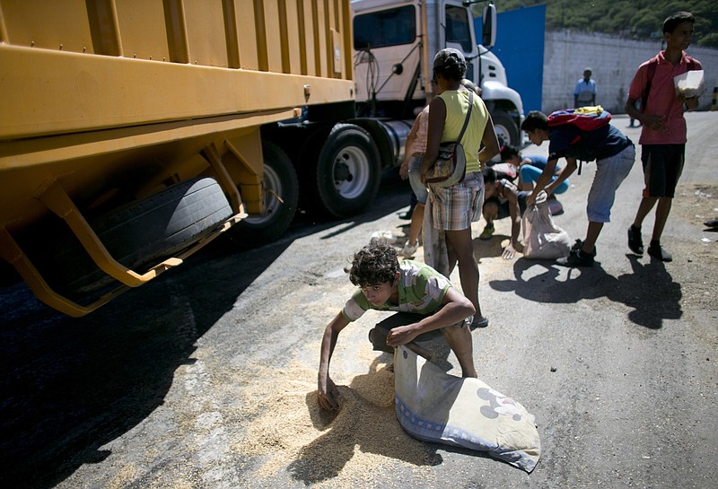 
              FILE - In this Nov. 14, 2016 file photo, a youth uses his pillow as a bag to collect rice from the pavement that shook loose from a food cargo truck waiting to enter the port in Puerto Cabello, Venezuela, the port that handles the majority of Venezuela's food imports. The calls by members of Congress on both sides of the aisle to sanction Venezuelan officials for profiting from food shortages come in response to an Associated Press investigation that found trafficking in hard-to-find food has become big business in Venezuela, with the military at the heart of the graft. (AP Photo/Ariana Cubillos, File)
            