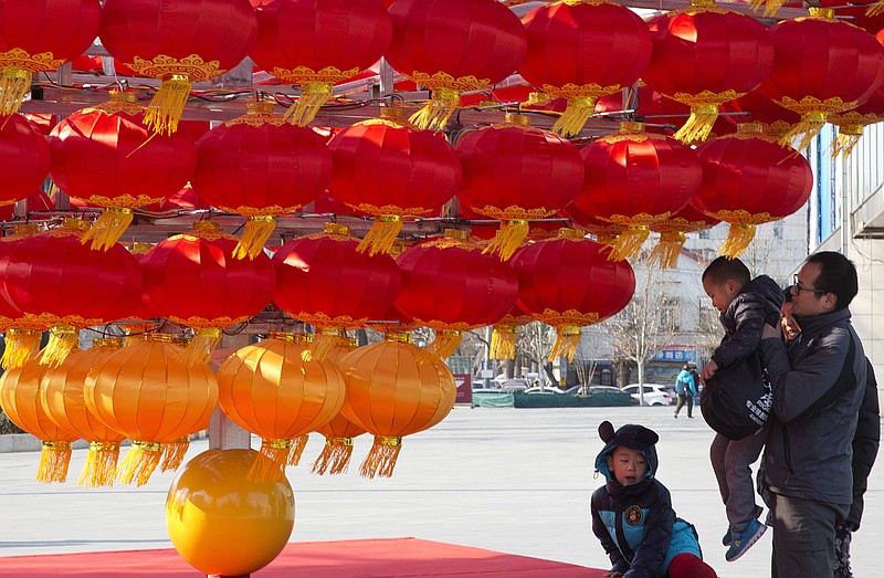
              In this photo taken Jan. 23, 2017, a man lifts a child up to lantern decorations setup ahead of the Chinese New Year in Beijing, China. China's National Health and Family Planning Commission said this week that 17.86 million children were born last year, an increase of 1.31 million from 2015. Nearly half of the children born were to couples who already had a child, the commission said. (AP Photo/Ng Han Guan)
            