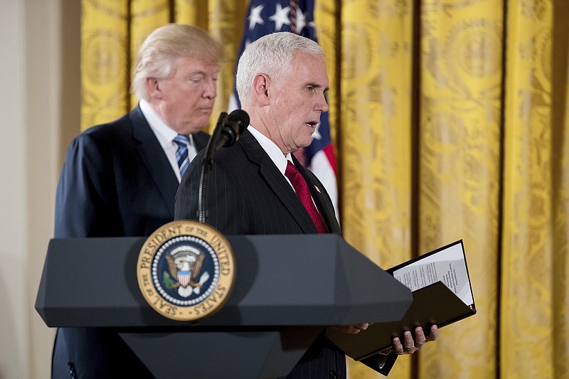 
              Vice President Mike Pence, right, accompanied by President Donald Trump, left, swears in White House senior staff during a ceremony in the East Room of the White House, Sunday, Jan. 22, 2017, in Washington. (AP Photo/Andrew Harnik)
            