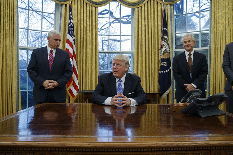 
              Vice President Mike Pence, left, and National Trade Council adviser Peter Navarro, right, wait for President Donald Trump to sign three executive orders, Monday, Jan. 23, 2017, in the Oval Office of the White House in Washington. (AP Photo/Evan Vucci)
            