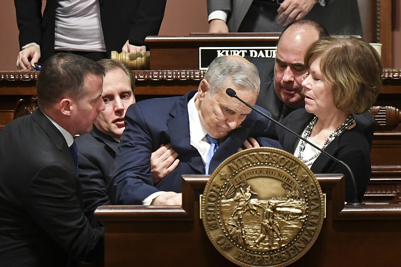 
              Minnesota Lt. Governor Tina Smith, right, and Secretary of State Steve Simon, left, help Minnesota Gov. Mark Dayton after he collapsed during his State of the State address in St. Paul, Minn., Monday, Jan. 23, 2017. House Speaker Kurt Daudt said minutes after the incident that Dayton was "up and about" and that the governor would be OK. (Glen Stubbe/Star Tribune via AP)
            