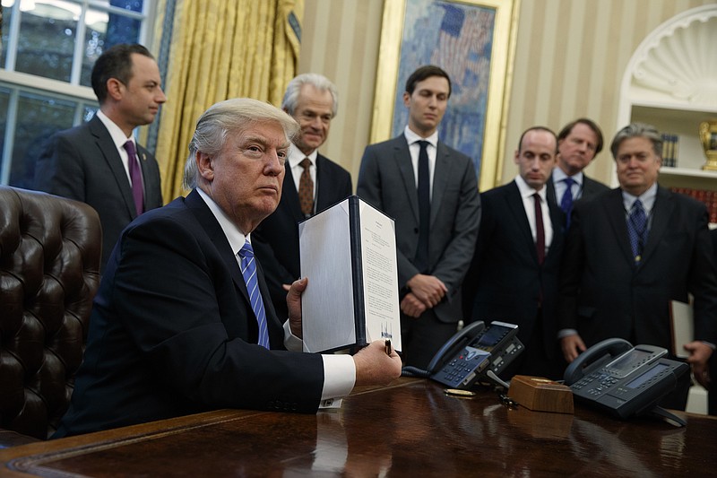 
              President Donald Trump shows off a signed executive order to reinstitute a policy barring any recipient of U.S. assistance from performing or promoting abortions abroad with money they receive from non-U.S. sources, Monday, Jan. 23, 2017, in the Oval Office of the White House in Washington. (AP Photo/Evan Vucci)
            
