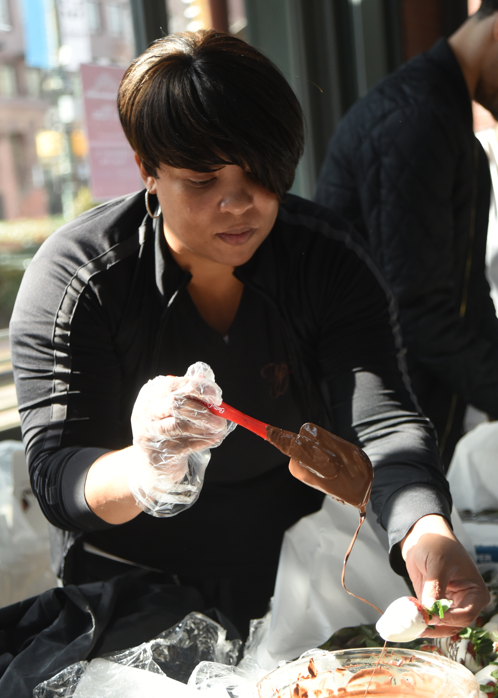 Antonia Poland, with Dipped Fresh, drizzles chocolate on strawberries during a Valentine's Day pop-up market Friday, February 12, 2016 at Miller Plaza.
