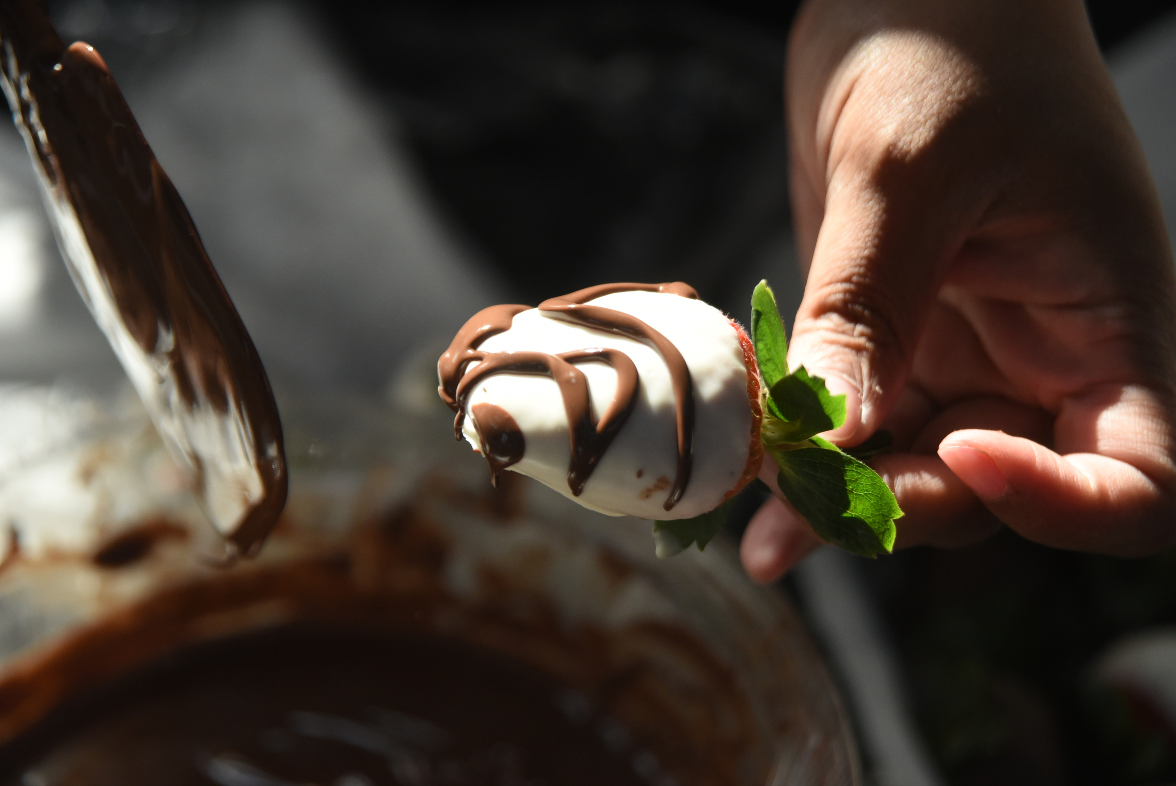 Antonia Poland, with Dipped Fresh, drizzles chocolate on strawberries during a Valentine's Day pop-up market Friday, February 12, 2016 at Miller Plaza.