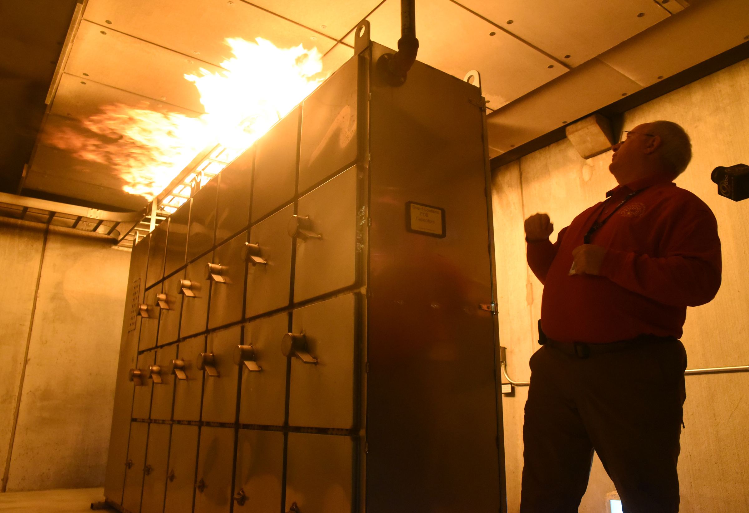 Phillip Johnson, manager of emergency response training at the Tennessee Valley Authority's Emergency Response Training Center, stretches back for a look at a test burn of the 480-volt electric board inside the Marion County facility during a media availability Tuesday.