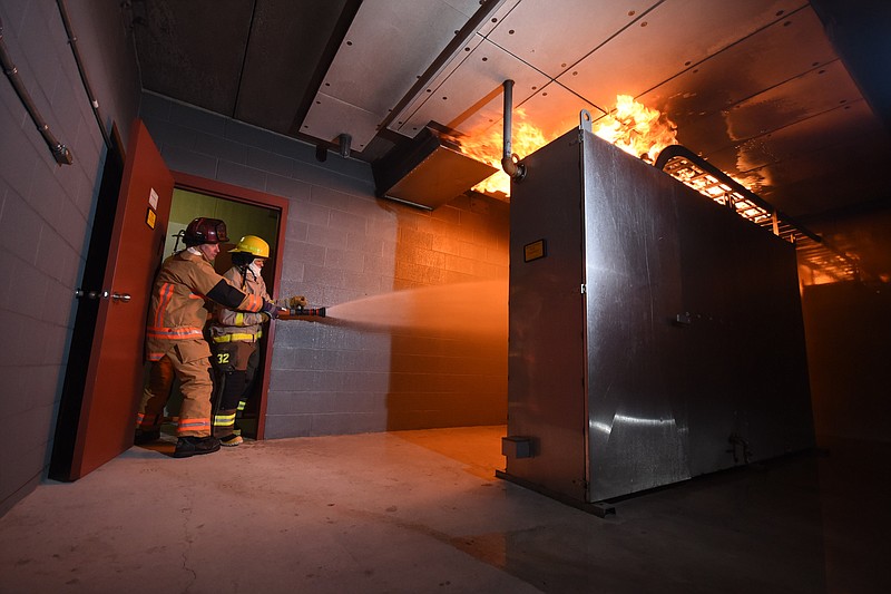 Level 3 Instructor Steve James, left, assists in a fire fighting training exercise inside a 480-volt board room Tuesday at the Tennessee Valley Authority's Emergency Response Training Center in Marion County.