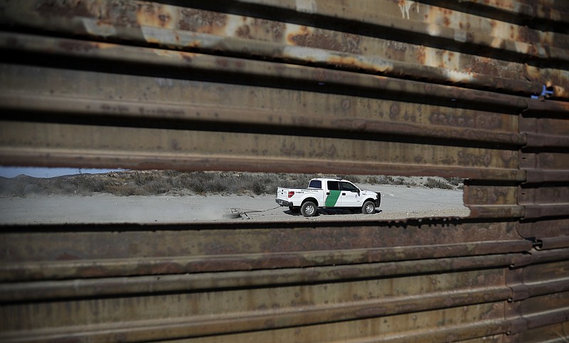 In this Nov. 9, 2016 file photo, a Border Patrol vehicle drives by in Tecate, Calif., seen through a hole in the metal barrier that lines the border in Tecate, Mexico. U.S. President Donald Trump will direct the Homeland Security Department to start building a wall at the Mexican border. (AP Photo/Gregory Bull, file)